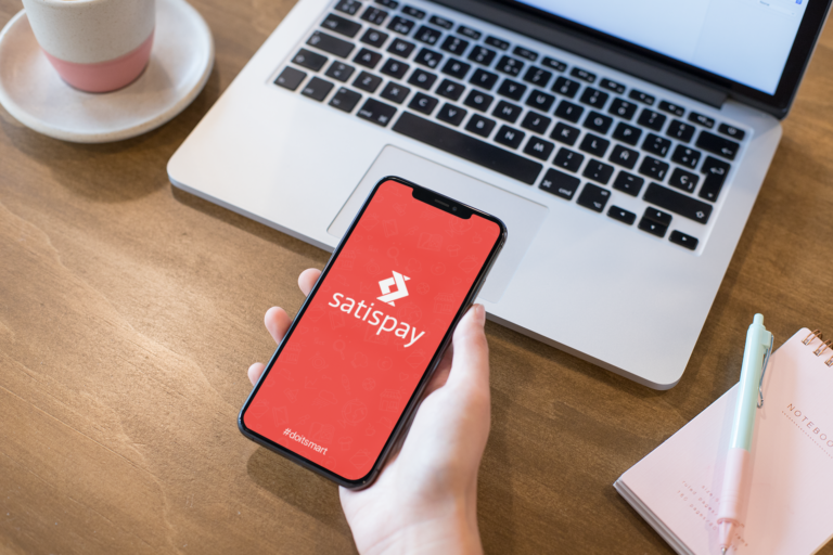 mockup-of-a-girl-s-hand-holding-an-iphone-xs-max-over-a-wooden-desk-25357